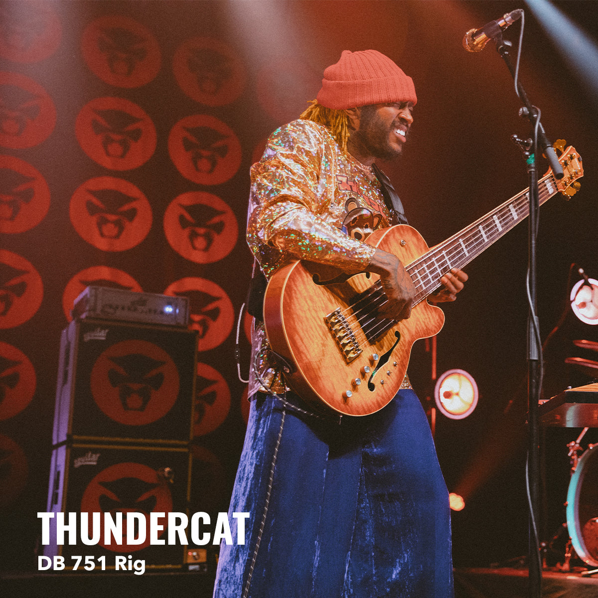 man on stage strumming the guitar with the aguilar bass amp